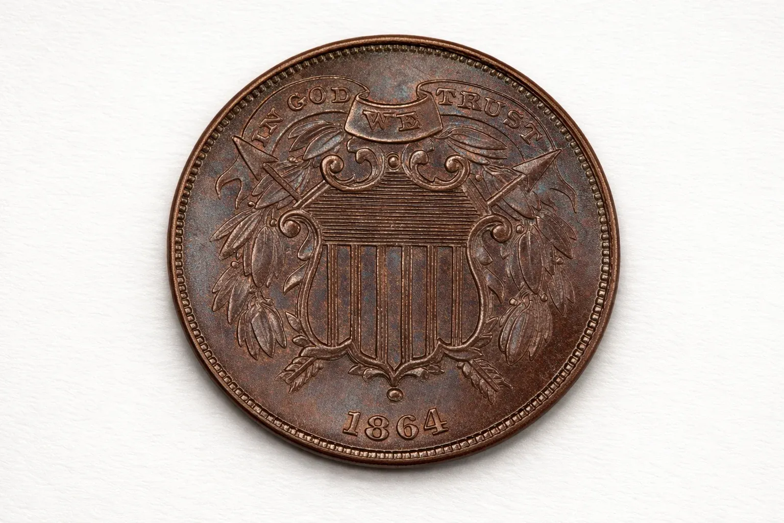Close-up of an 1864 two-cent piece showing the shield design and the motto “In God We Trust.”